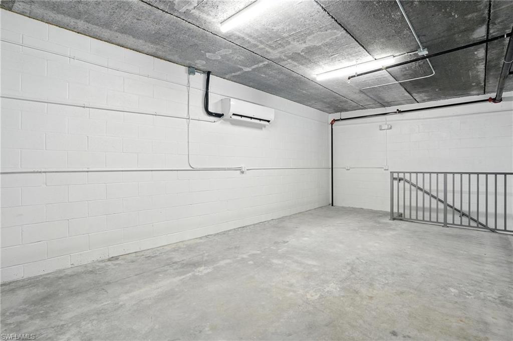 Unfinished interior space featuring painted concrete block walls, a concrete floor, and an exposed concrete ceiling