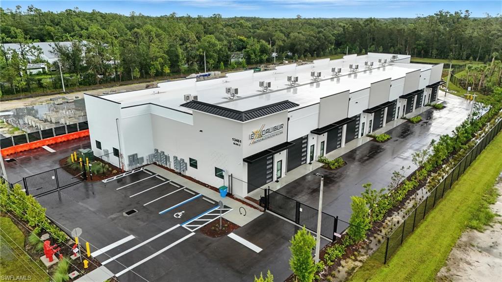 Modern commercial building featuring multiple bay doors, a paved parking area, and perimeter fencing