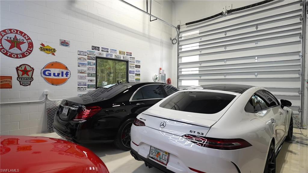 Spacious garage featuring white block walls, a large window, and a metal roll-up door