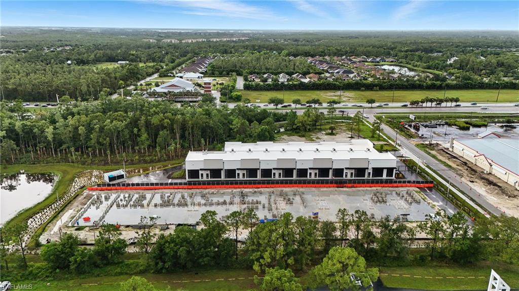 Modern industrial building featuring multiple loading docks, an expansive paved lot, and a surrounding natural landscape