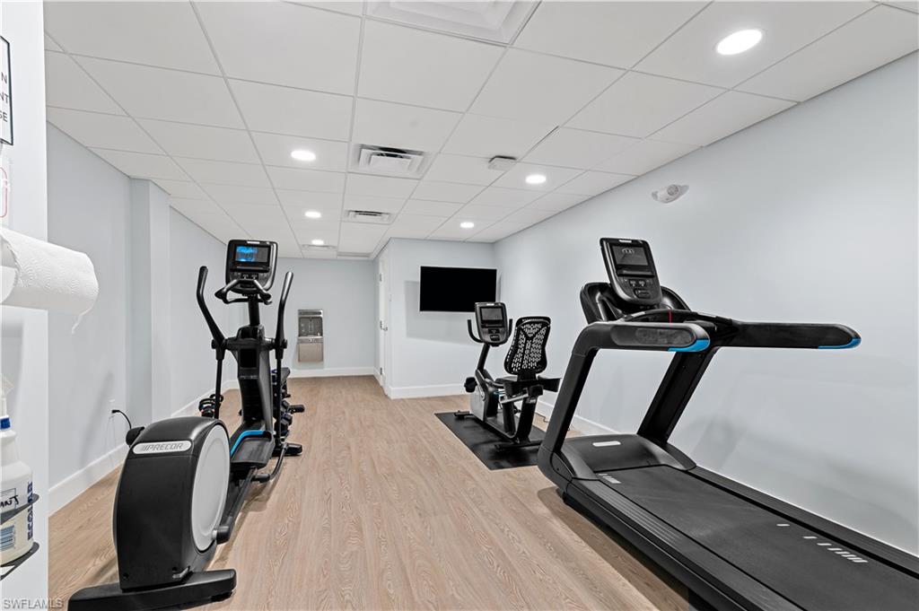 Fitness area featuring wood-finish flooring, recessed lighting, and a drop ceiling