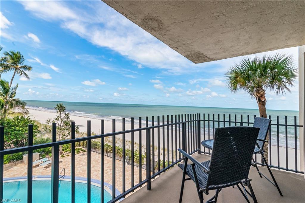 Balcony with black metal railings, overlooking the sandy beach and ocean