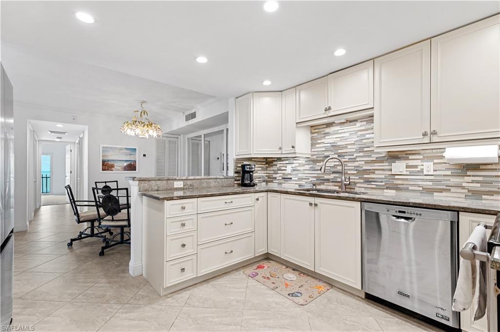 Modern kitchen featuring white cabinetry, stainless steel appliances, a horizontal tile backsplash, granite countertops, and recessed lighting