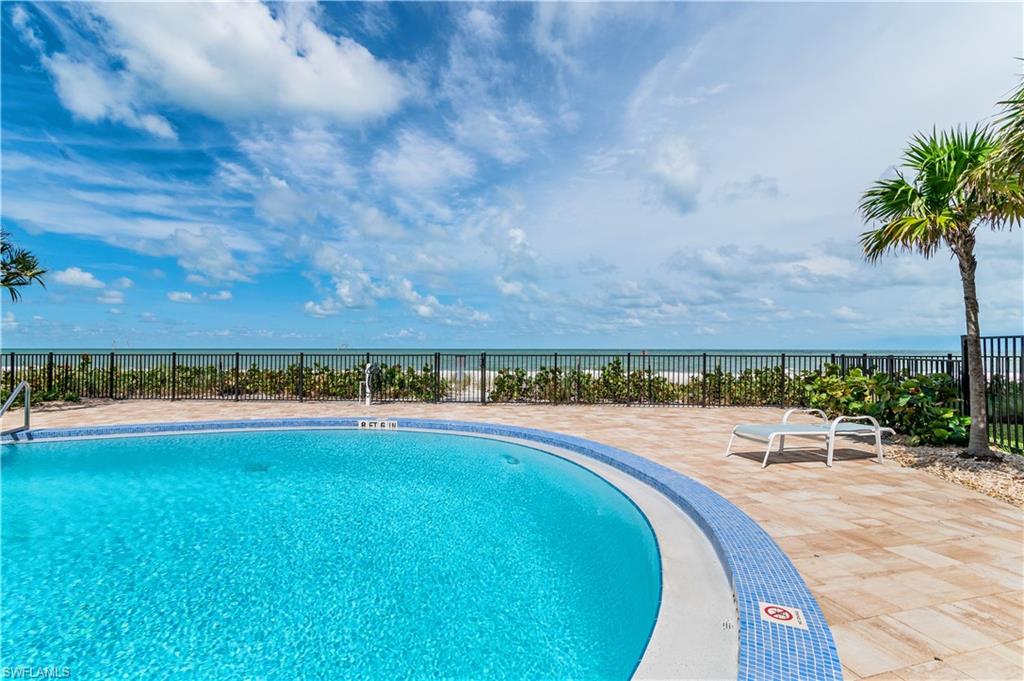 Outdoor swimming pool with mosaic tile trim, paver decking, and a perimeter fence