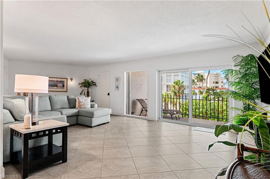 Spacious living area featuring large format tile flooring, a built-in wall sconce, and white walls
