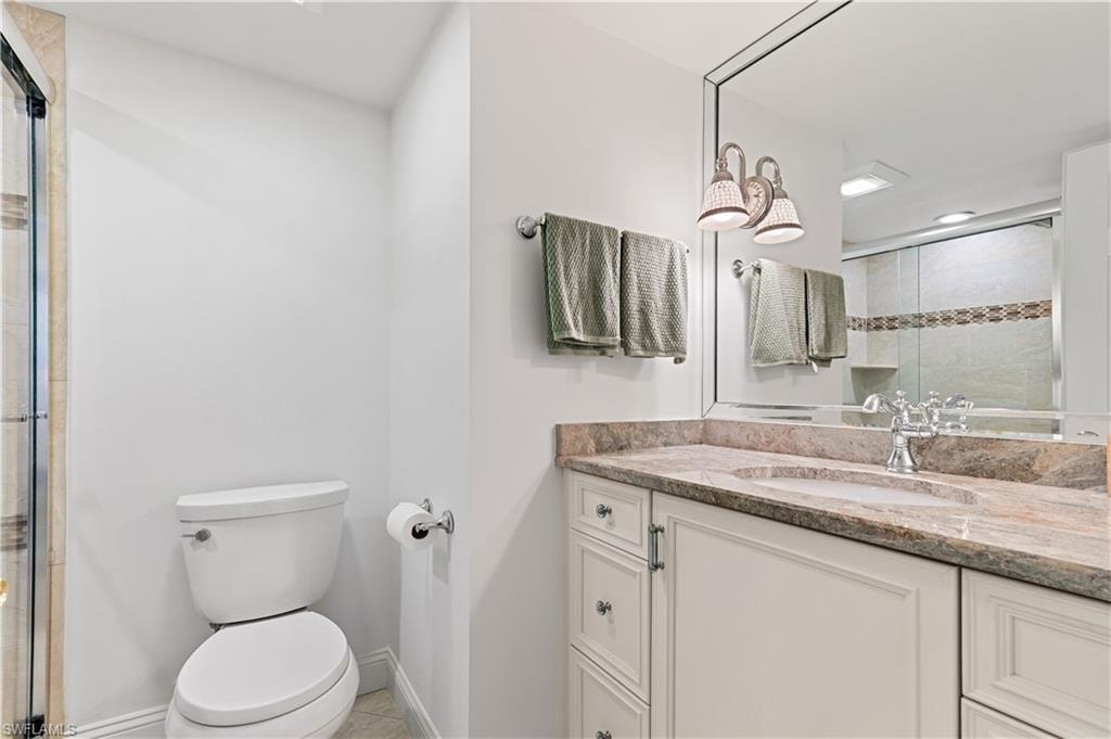 Bathroom vanity featuring a polished stone countertop with an undermount sink, dual-handle faucet, and framed mirror