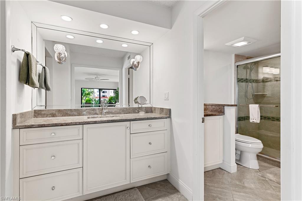 Bathroom featuring a dual-sink vanity with a stone countertop, white cabinetry, and an expansive mirror