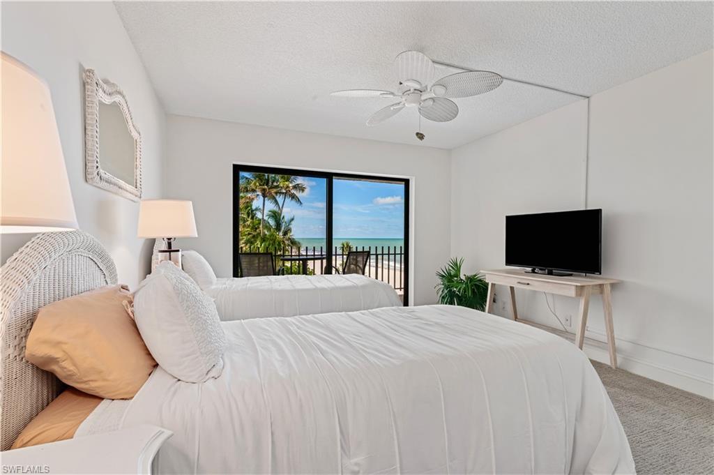 Sliding glass doors opening to a private balcony with water and palm tree scenery