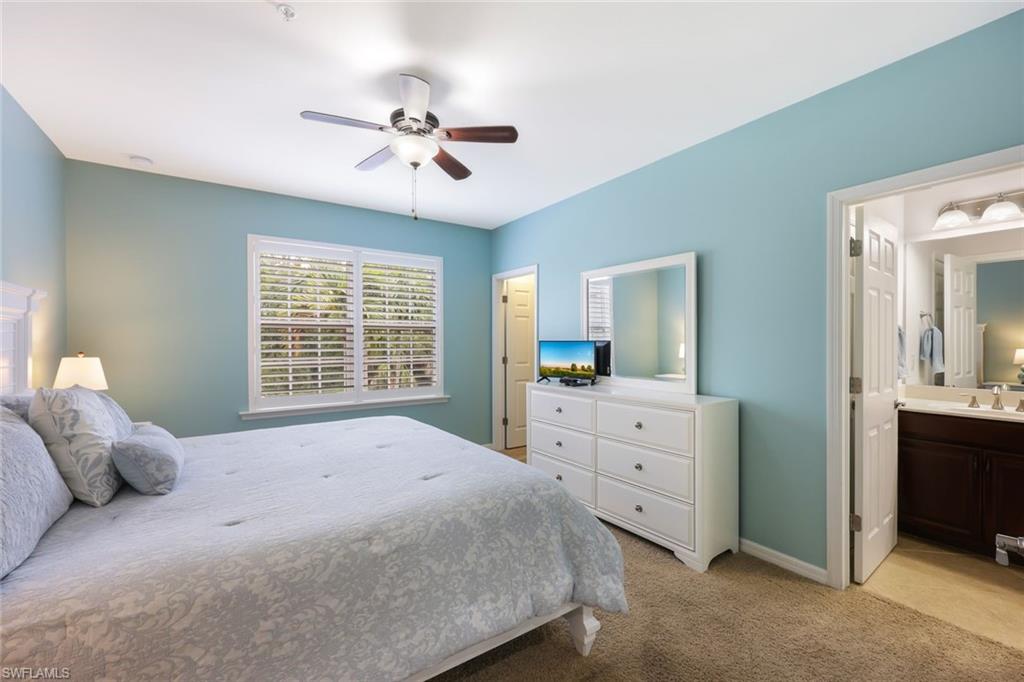 Bedroom with light carpet, connected bathroom, ceiling fan, and sink
