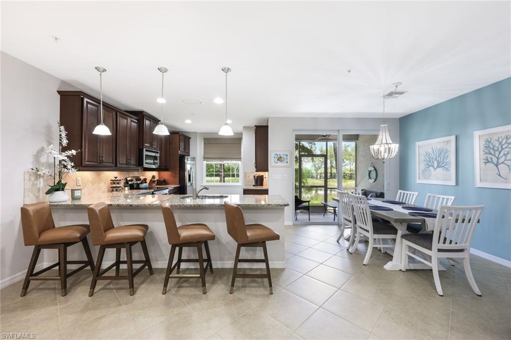 Kitchen featuring decorative backsplash, light tile patterned floors, light stone counters, and stainless steel appliances