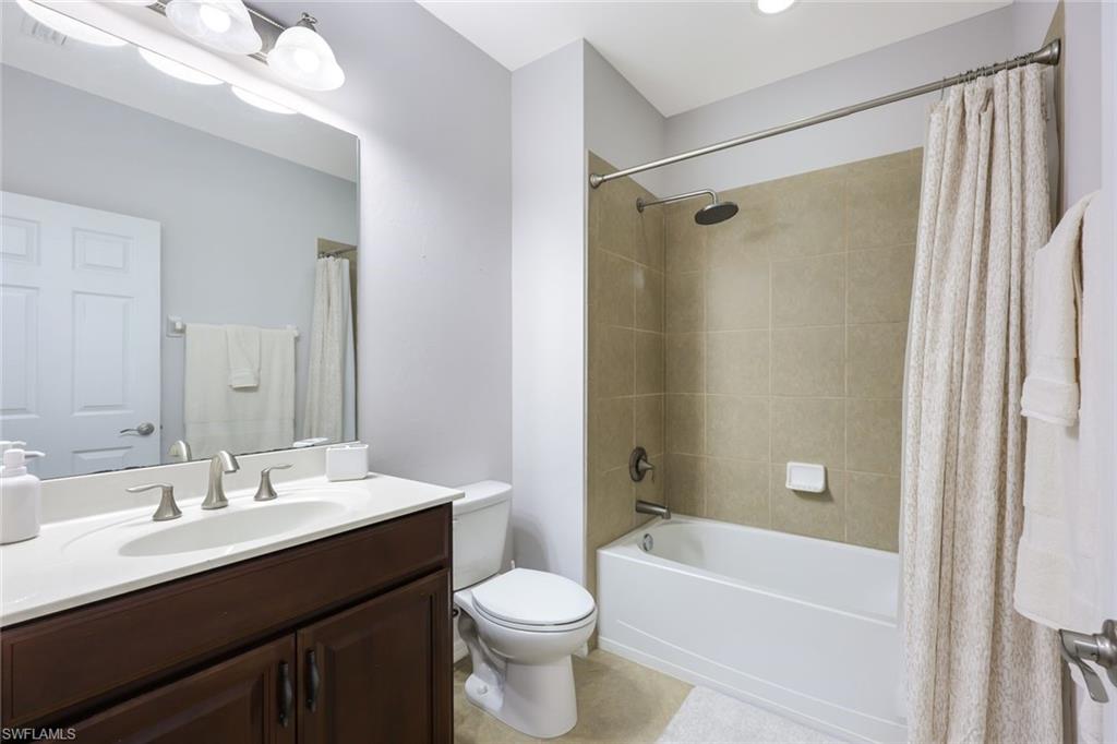 Full bathroom featuring vanity, toilet, shower / bathtub combination with curtain, and tile patterned floors