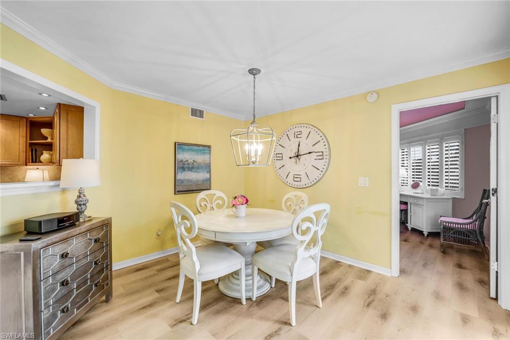 Dining room featuring a chandelier, light wood-type flooring, and ornamental molding