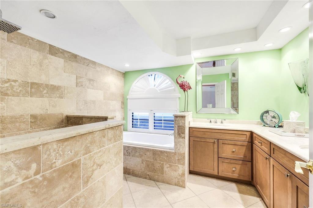 Bathroom with vanity, tile patterned floors, and a relaxing tiled tub