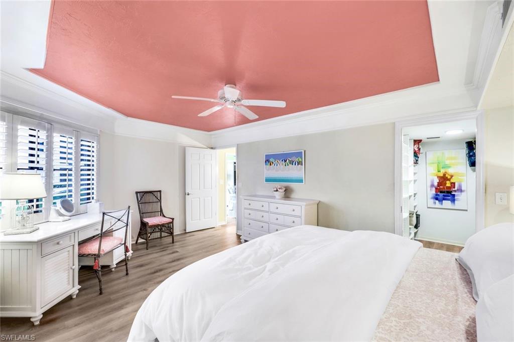 Bedroom with light hardwood / wood-style flooring, ceiling fan, a raised ceiling, and crown molding