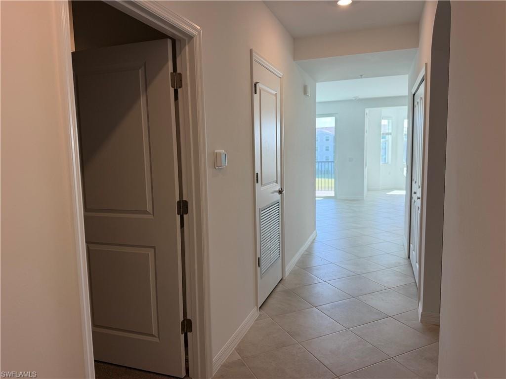 Hallway featuring neutral-toned tile flooring, recessed lighting, and white paneled doors