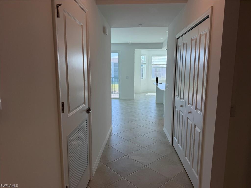 Hallway featuring diamond-patterned tile flooring, white walls, and a white six-panel bifold closet door