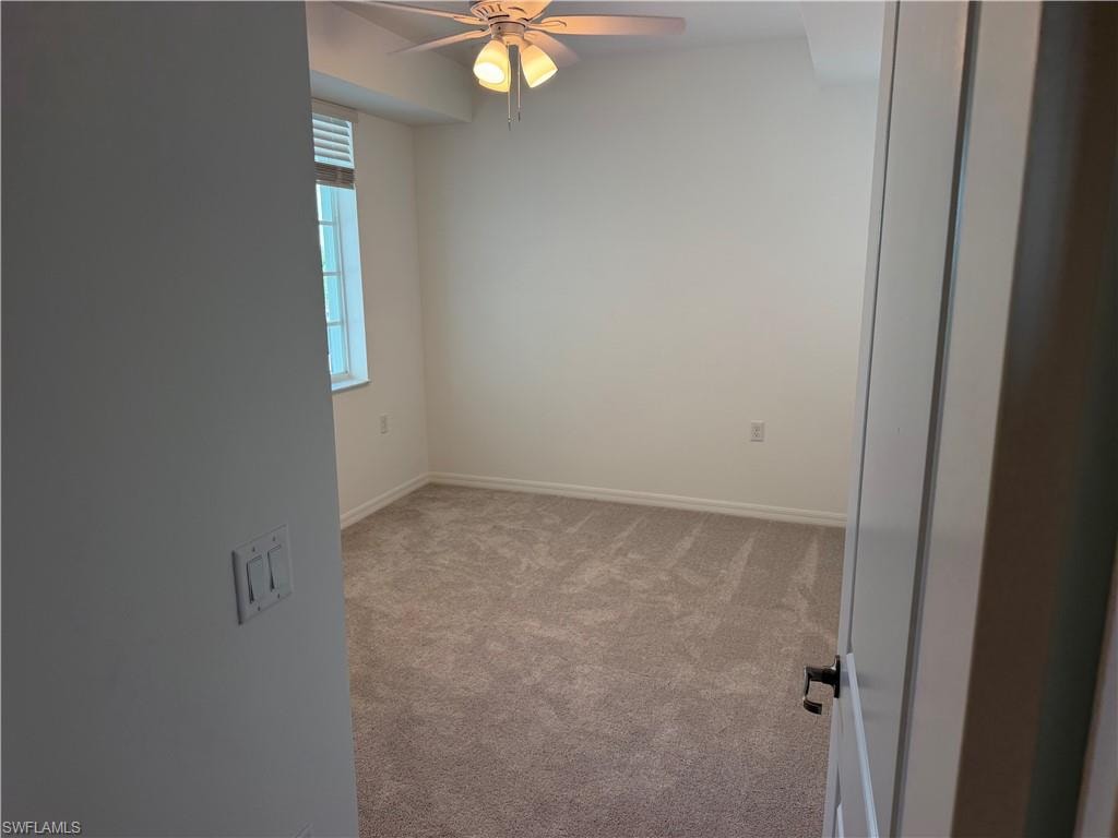 Carpeted room featuring a ceiling fan with light fixture, window with blinds, and neutral wall paint