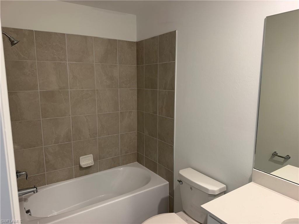 Full bathroom featuring a white bathtub, beige tiled shower surround, chrome fixtures, and a white toilet