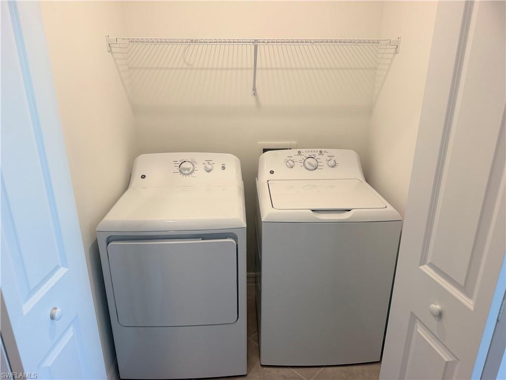 Dedicated laundry area featuring a white GE washer and dryer set, overhead wire shelving, and neutral wall tones