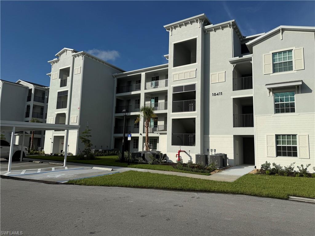 Multi-story building featuring light grey stucco and white horizontal siding with decorative shutters