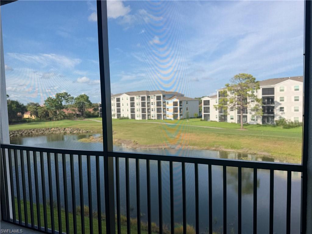 Screened balcony featuring a black metal railing and a body of water