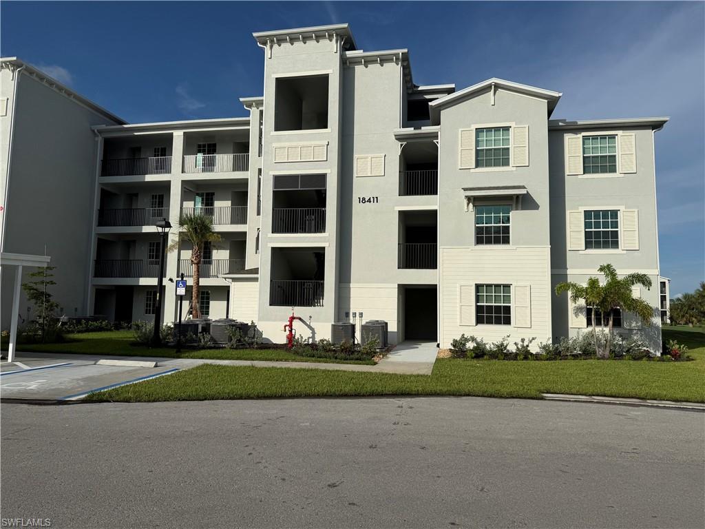 Multi-story condominium building featuring light gray stucco and light beige siding