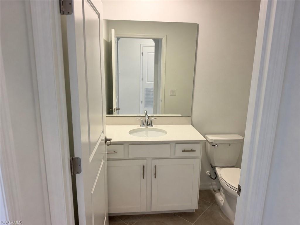 White vanity with a single basin, light-toned countertop, and chrome faucet