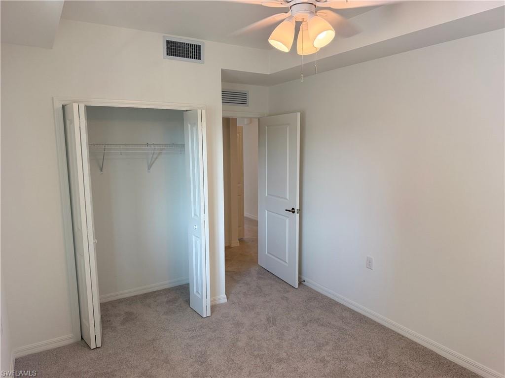 Neutral-toned carpeting and white walls complement the closet with bi-fold doors and wire shelving
