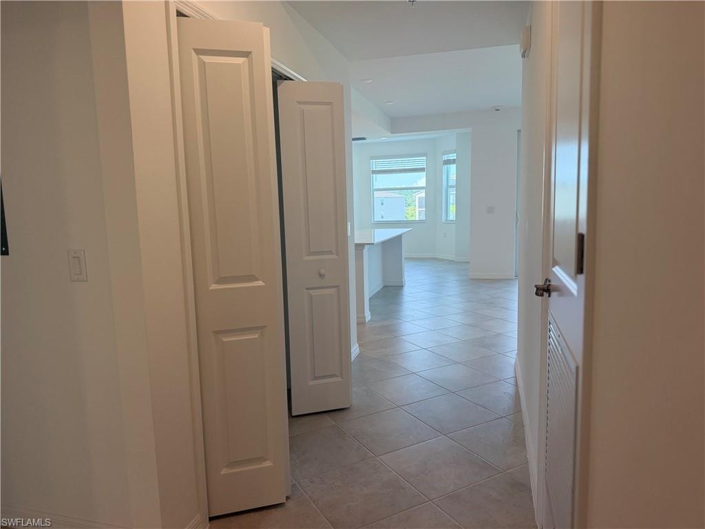Hallway with diagonal tile flooring leading to an open-concept area featuring a kitchen island and bay windows