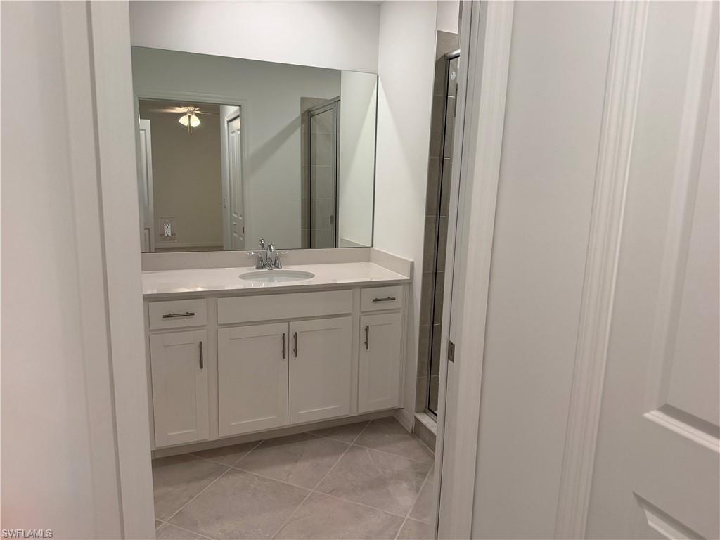Contemporary bathroom featuring a single white vanity with a light-toned countertop, an integrated sink, and brushed nickel hardware