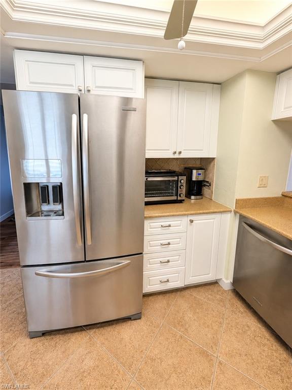 Kitchen featuring stainless steel appliances, white cabinetry, a light-toned countertop, and tile flooring