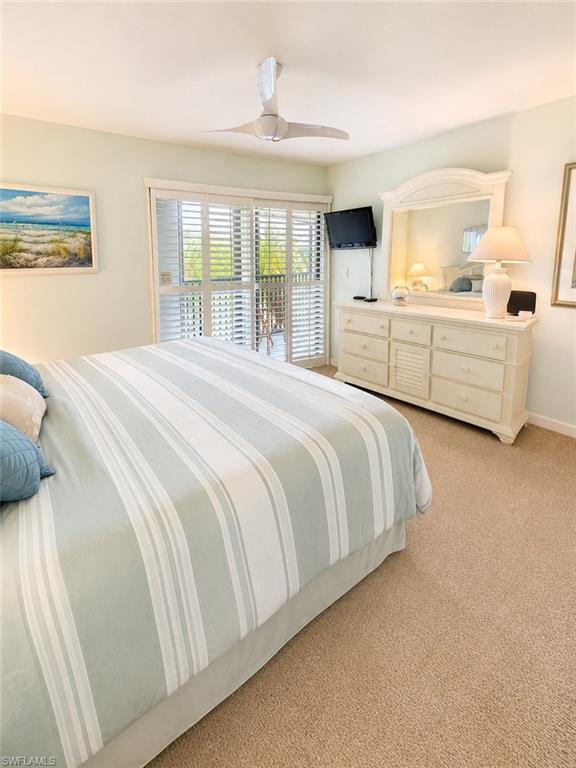 Bedroom featuring plush carpeting, a ceiling fan, and sliding glass doors with plantation shutters opening to an outdoor balcony