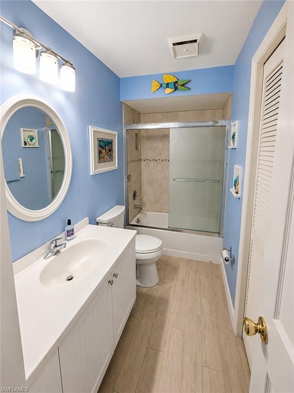 Bathroom with a white vanity featuring an integrated sink, a large oval mirror, and a three-light fixture