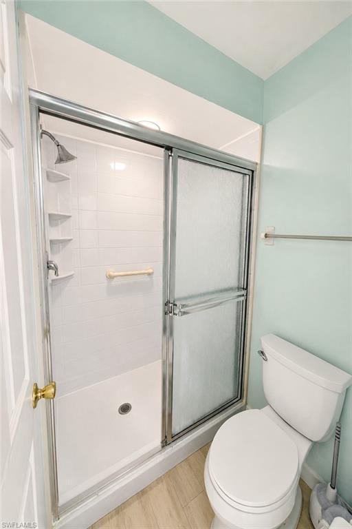 Shower enclosure with sliding glass doors, white subway tile surround, built-in shelving, and a chrome shower head