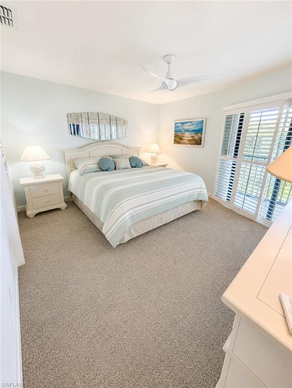 Carpeted bedroom featuring a ceiling fan, white plantation shutters, and a light color palette