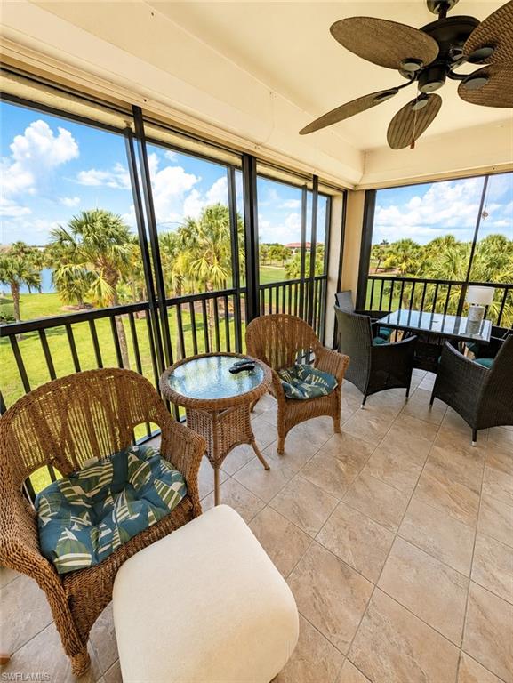Screened-in balcony featuring neutral-toned floor tile and a ceiling fan