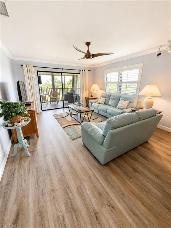 Living area featuring wood-finish flooring, a ceiling fan, and crown molding