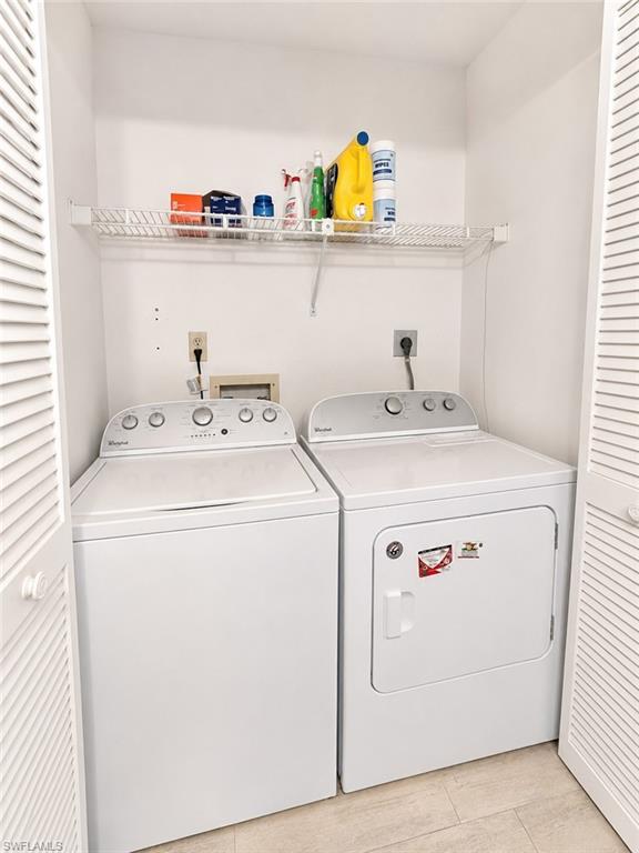 Dedicated laundry area featuring a white washing machine, white dryer, and a wall-mounted wire shelf