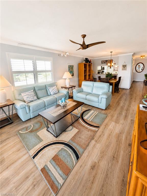 Spacious living area featuring wood-finish flooring, plantation shutters, and a modern ceiling fan