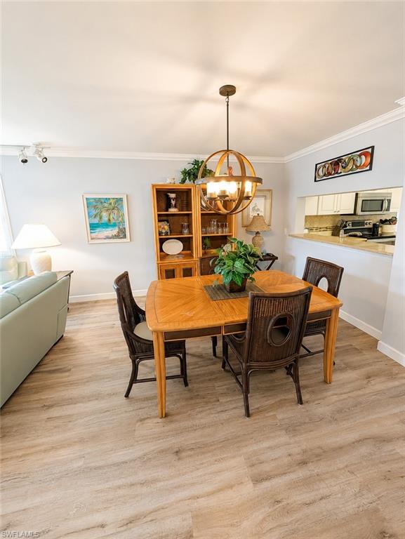 Dining area featuring wood-finish flooring, a contemporary spherical chandelier, and crown molding