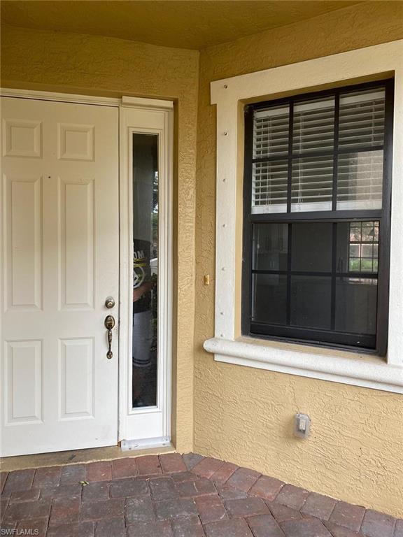 Entryway featuring a white paneled door with sidelight, decorative hardware, and a window with black grilles