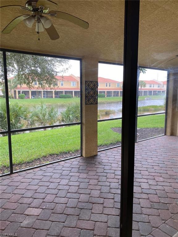 Screened lanai featuring multi-tone paver flooring, a ceiling fan, and direct water frontage