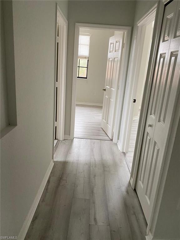 Hallway featuring light-toned wood-finish flooring