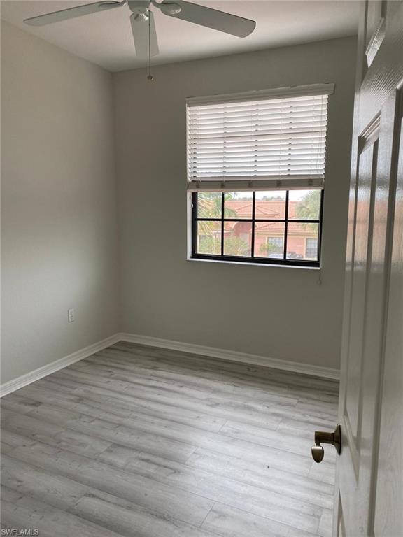 Room featuring light gray walls, wood-finish flooring, a window with horizontal blinds, and a ceiling fan with integrated lighting
