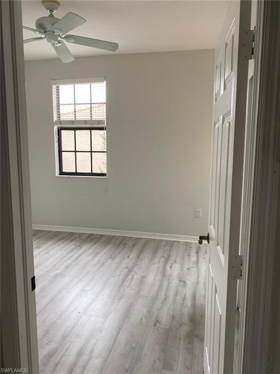 Spacious room featuring wood-finish flooring, light-toned walls, and a ceiling fan
