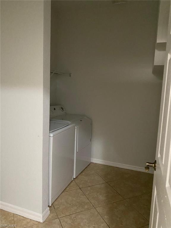 Dedicated laundry room featuring tile flooring, white front-load washer and dryer units, chrome towel rod, and ample wall shelving for storage and organization