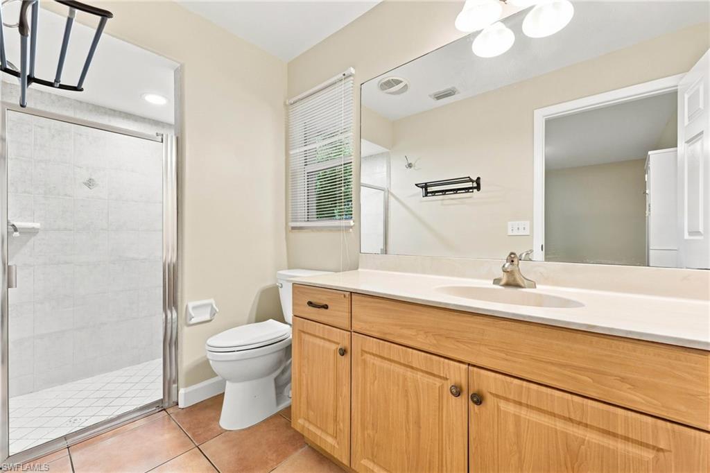 Spa-inspired primary bathroom featuring a wood-finish vanity with dual sinks, white quartz countertop, and polished chrome fixtures