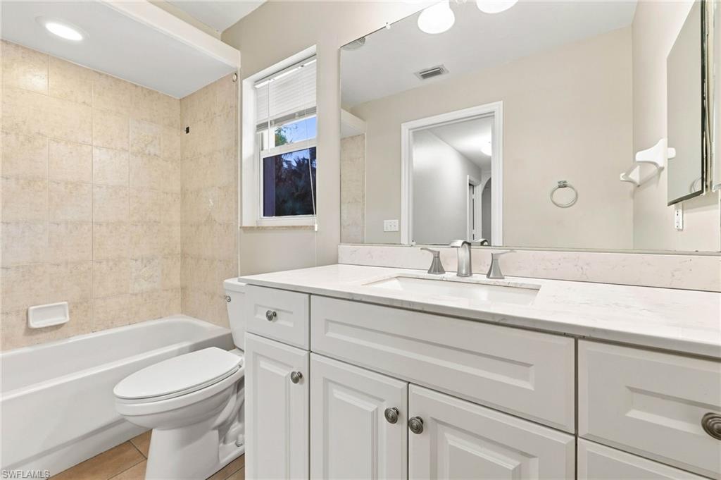 Spa-inspired primary bathroom featuring a white shaker-style vanity with dual sinks, quartz countertop, and polished chrome hardware