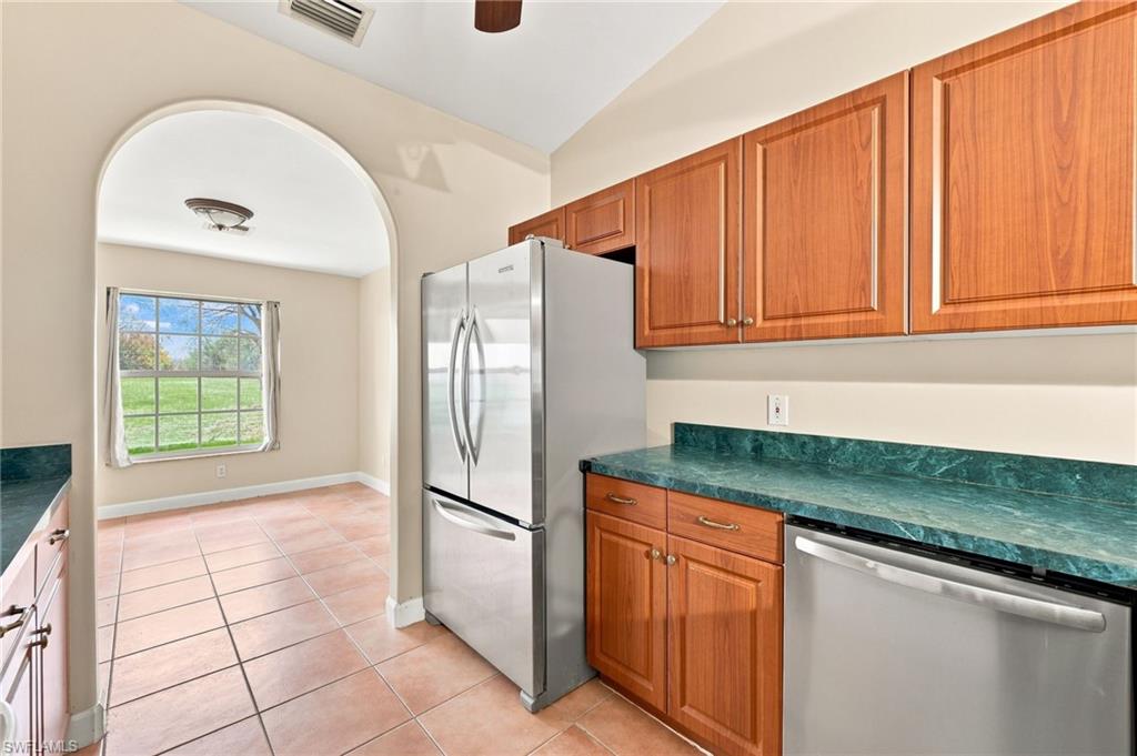 Kitchen featuring wood-finish cabinetry, green marble-look countertops, and stainless steel appliances including a refrigerator and dishwasher