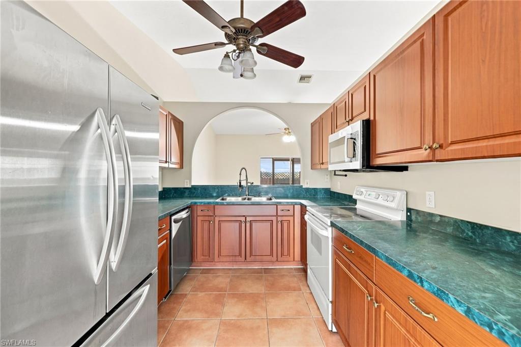 Galley kitchen featuring warm wood cabinetry, teal tile backsplash, and matching teal countertops